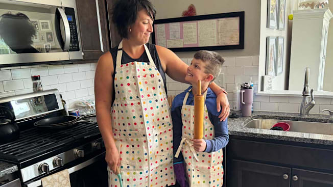 a mom and son wearing matching aprons in a kitchen