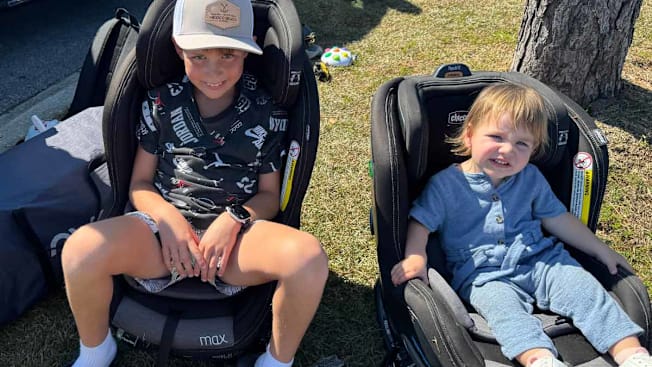 a child and a toddler sitting in car seats outside of a car