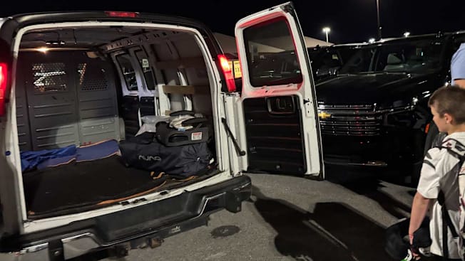 a van filled with rental baby and child gear in a parking lot next to a child and their parent