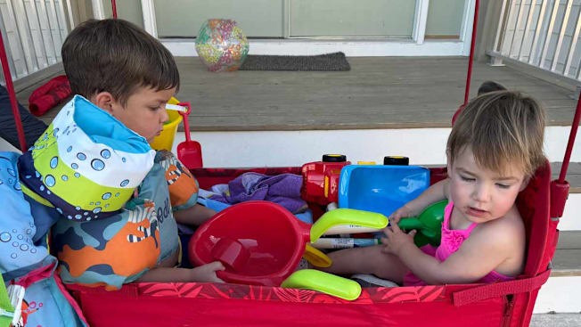 two young children in a wagon with beach toys