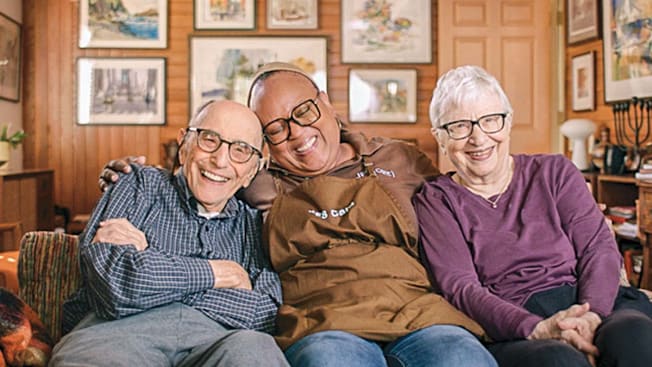 Jack and Judy Rothman with their
home health aide, Lynn Anderson, sitting on a couch