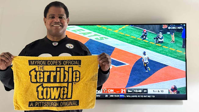 CR Editor Keith Flamer holding a Pittsburgh Steelers "Terrible Towel" in front of a TV with a football game playing in the background