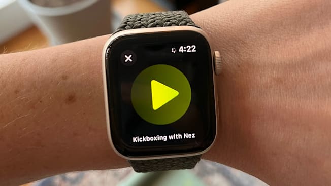 close up of person's wrist wearing Apple Watch showing screen saying "Kickboxing with Nez" and play button