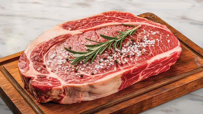 Raw steak on cutting board with coarse salt and pepper
