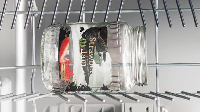 A photo illustration showing an old jar inside of a dishwasher with the label peeling off.