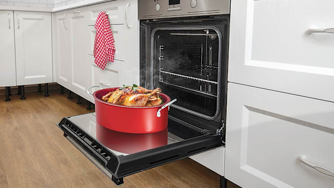 A photo illustration showing a heavy pan being placed on an open oven door.