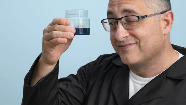 Laundry expert Rich Handel holding a measuring cup with laundry detergent to show how little you need to get your clothes really clean.