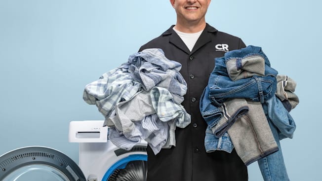 Laundry expert Rich Handel holding two piles of laundry sorted by colors and fabric weight.