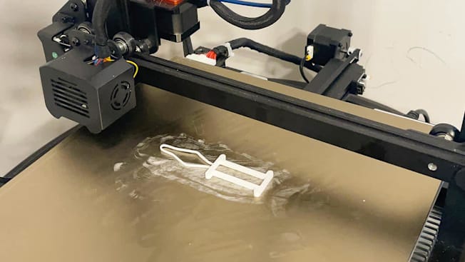 An adaptive button tool sitting on a 3D printer.
