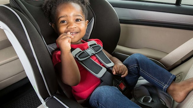 toddler in rear-facing car seat with 5-point harness, toddler wearing red shirt and jeans