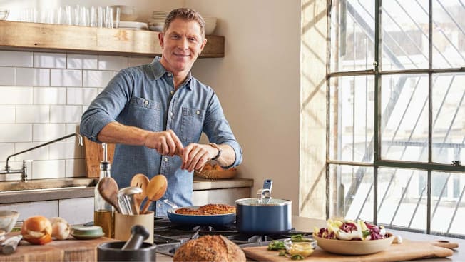 Bobby Flay in a bright kitchen setting cooking.
