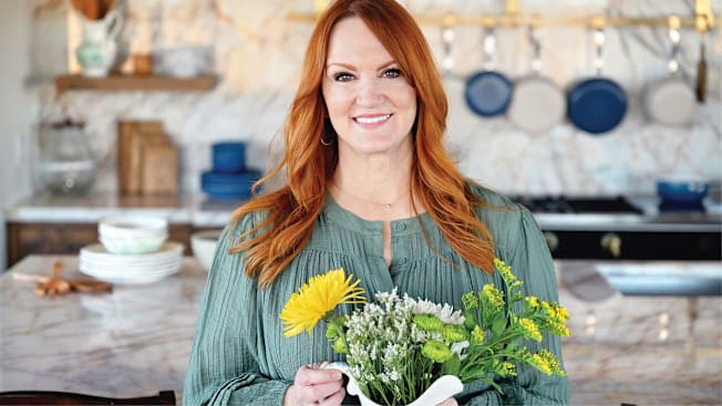 Ree Drummond in a kitchen holding a bouquet of flowers