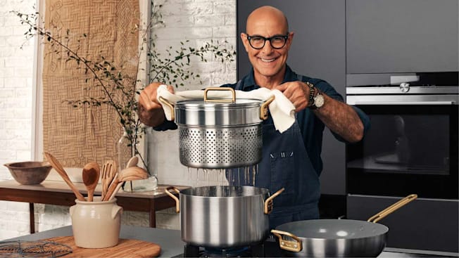 Stanley Tucci in a kitchen draining pasta