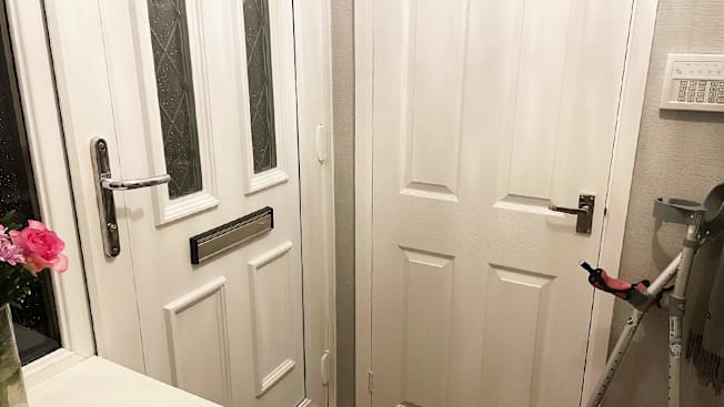 An entryway showing a front door with a level-type door handle and crutches leaning on the wall.