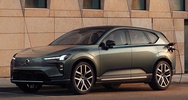 2027 Volvo EX60 EV plugged-in alongside a building