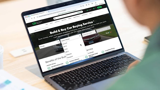 A person scrolling through the Consumer Reports website on a laptop.