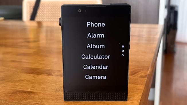 Light Phone III on wooden table with menu on screen