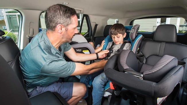 Father buckling his son into the middle car seat.