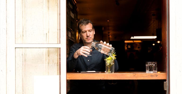 A man at a counter pouring some kind of liquid.