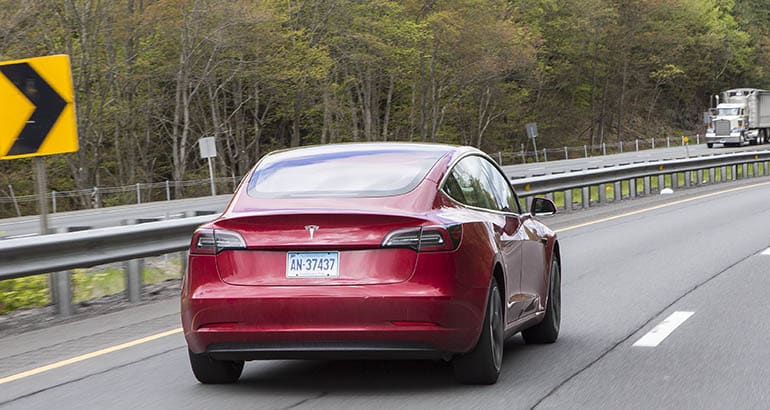 Tesla Model 3 on highway, from rear