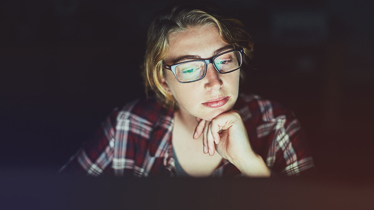 Facebook user, a young woman with face illuminated by laptop screen