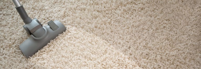 Photo of a vacuum cleaner removing dirt from a rug.