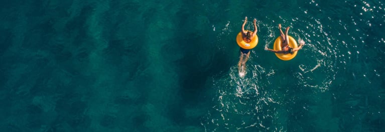 Two people in tubes in the water, practicing sun safety on vacation.