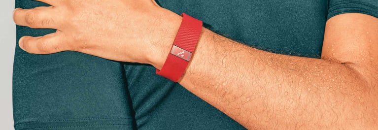 A photo of a red fitness tracker band on the wrist of a man.
