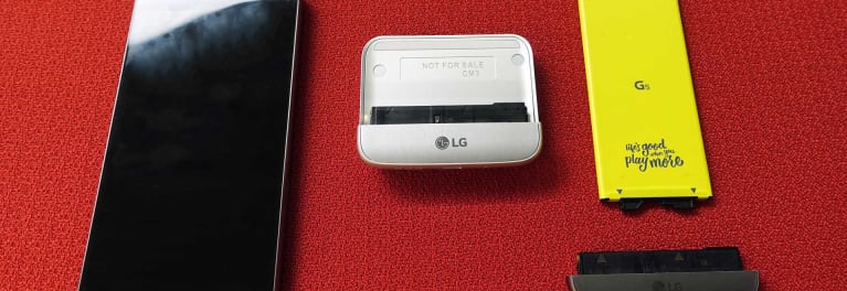 The LG G5 smartphone disassembled, showing the top and bottom portion of the phone next to the battery and CAM Plus camera module.