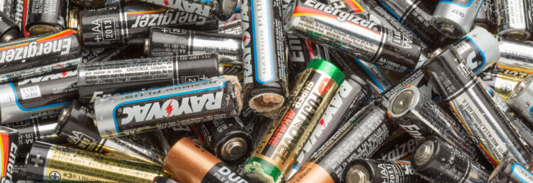 A pile of leaking AA batteries with potassium carbonate crust on their shells