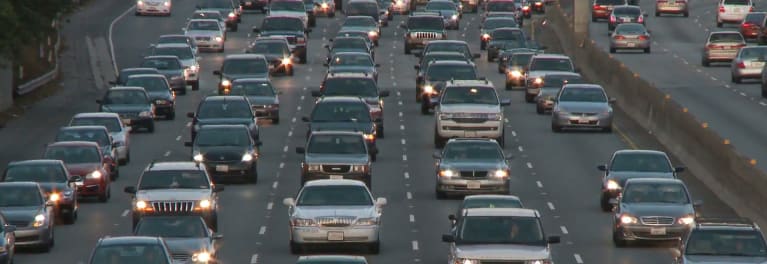 A photo of many cars sitting in highway traffic.