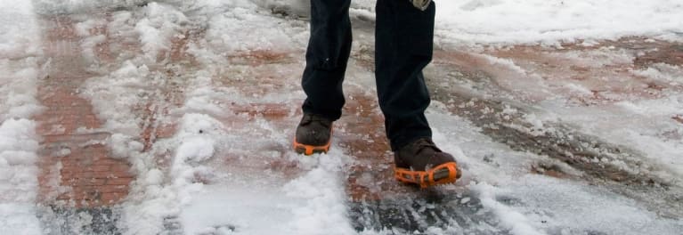 Someone clearing snow wearing ice cleats.
