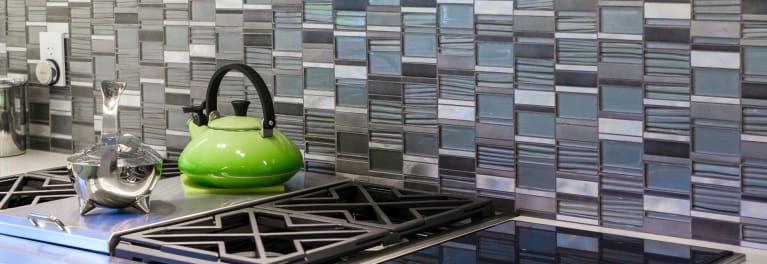 A stove with a green tea kettle.