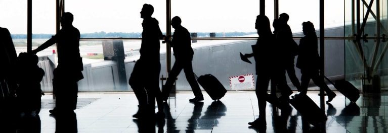 Silhouettes of people at an airport.